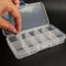A hand is opening a clear plastic container with multiple compartments, which appears to be a storage or organization tool.