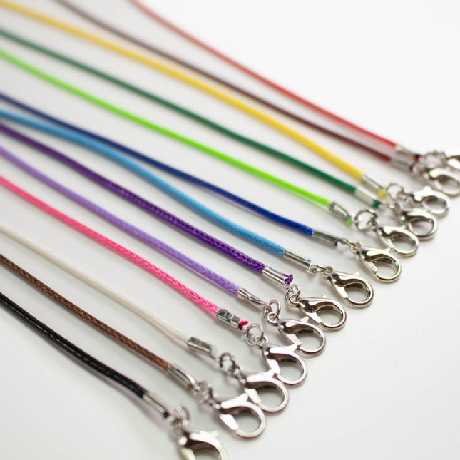 A row of colorful braided strings with metal clasps arranged on a white background.