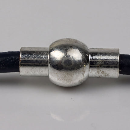 A close-up view of a silver-colored metal connector or clasp attached to a black cord or chain.