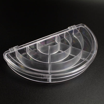 A clear plastic container with multiple compartments, sitting on a black surface.