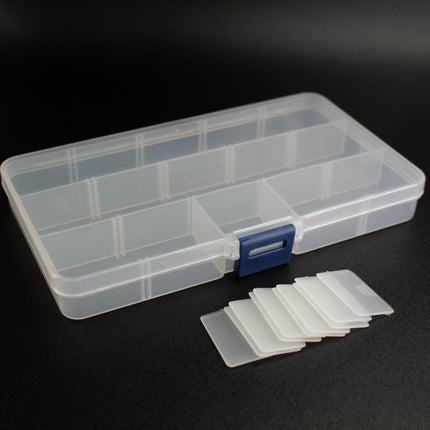 A clear plastic storage container with multiple compartments, accompanied by several white plastic cutout pieces, all placed on a black surface.