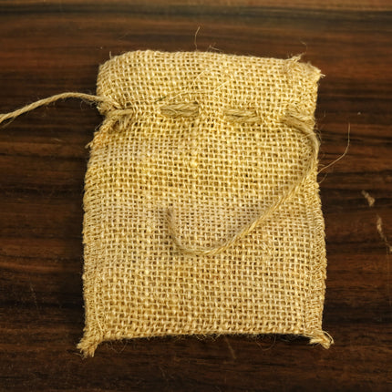 A burlap sack with a rope tied around it, sitting on a wooden surface.