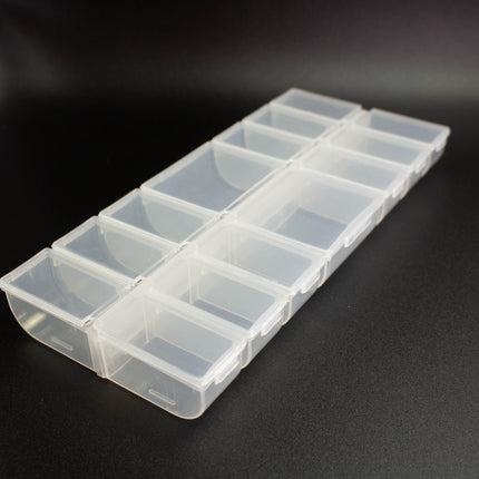 A clear plastic container with multiple compartments, sitting on a black surface.