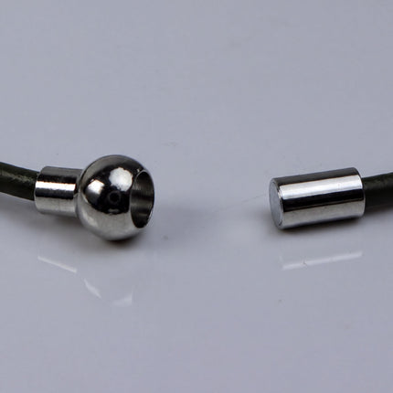 a close-up view of a metallic object with a round, shiny surface, lying on a white surface.