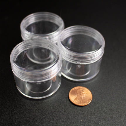 three clear plastic containers and a penny on a black surface.