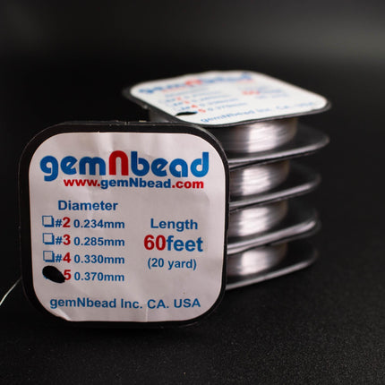 a close-up of a package of silver thread from the company gemNbead, with a focus on the label that provides information about the thread's dimensions and length.