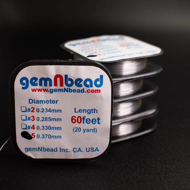 a close-up of a package of silver thread from the company gemNbead, with a focus on the label that provides information about the thread's dimensions and length.