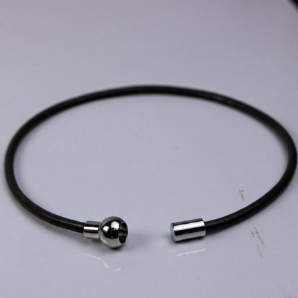 A black cord bracelet with a silver clasp is shown in the image.