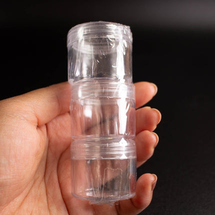 A hand holding a clear plastic container with three smaller containers inside.