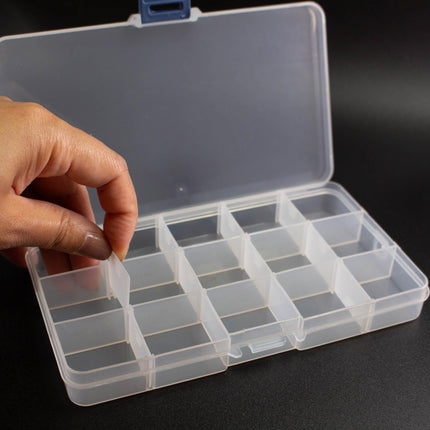 A hand is opening a clear plastic container with multiple compartments, likely for organizing or storing items.