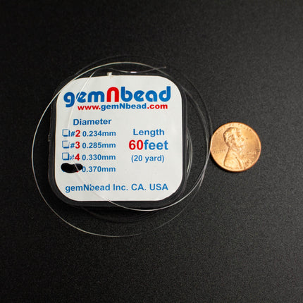 a clear measuring tape wrapped around a piece of jewelry, with a penny placed next to it to provide a sense of scale.