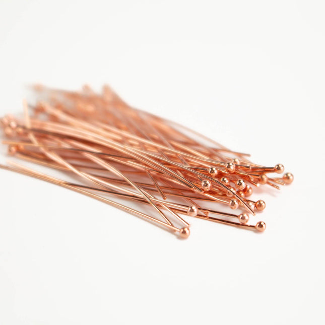 A pile of copper-colored metal pins or needles on a white background.