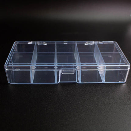 A clear plastic container with multiple compartments is shown on a dark surface.