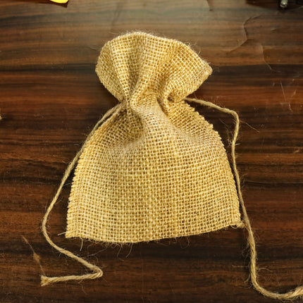 A burlap sack with a woven texture is placed on a wooden surface.