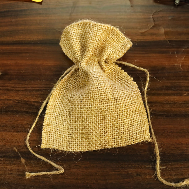 A burlap sack with a woven texture is placed on a wooden surface.