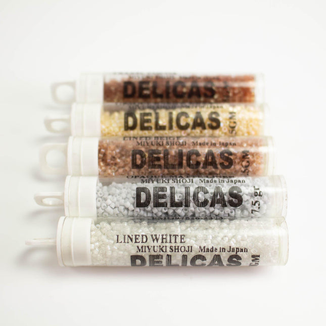 five containers of Delicas brand beads, each with a different color and size.