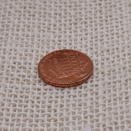 A single penny is resting on a woven surface.