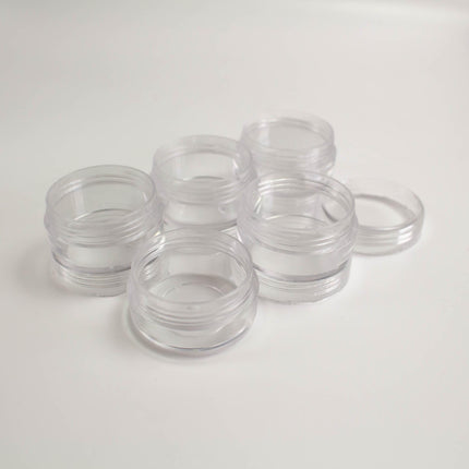 A group of clear plastic containers or jars is arranged on a white surface.