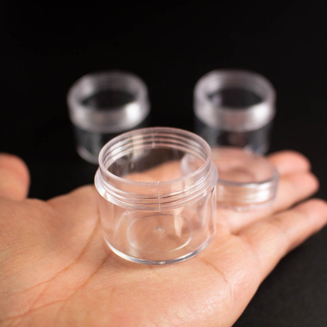 A hand holding a clear plastic container against a dark background.