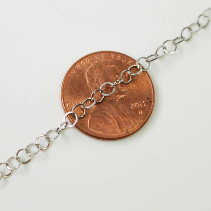 A close-up image of a chain necklace with a penny placed on top of it, indicating the necklace is approximately the size of a penny.