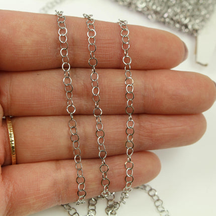 A close-up image of a person's hand holding a silver chain with multiple links, against a white background.