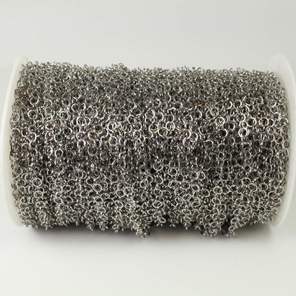 A spool of silver-colored metal chain with numerous small circular links.