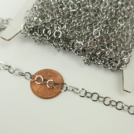a close-up view of a silver chain with multiple links, placed next to a penny.
