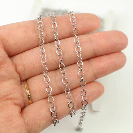 A hand holding a silver chain necklace with multiple silver links.