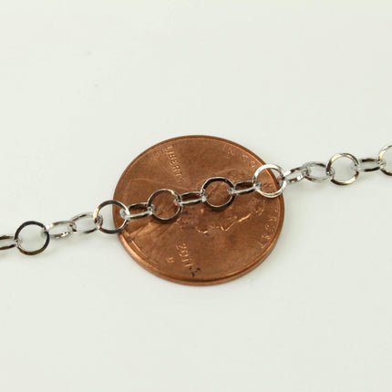 A close-up image of a silver chain resting on top of a copper-colored penny.