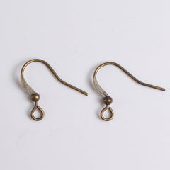 Two antique-looking brass earring hooks with curved ends and small round balls at the bottom.