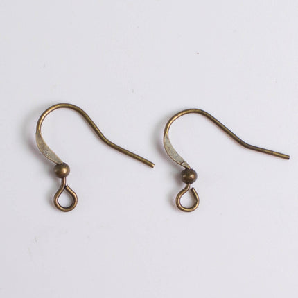 Two antique-looking brass earring hooks with curved ends and small round balls at the bottom.