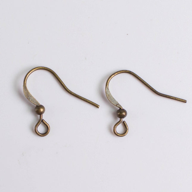 Two antique-looking brass earring hooks with curved ends and small round balls at the bottom.