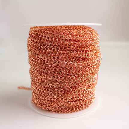 A spool of copper-colored chainmail is shown against a plain white background.