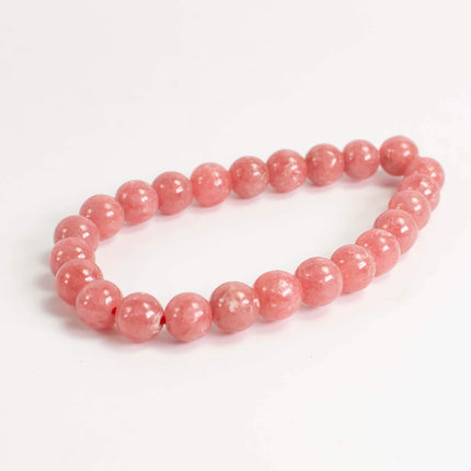 A bracelet made of pink beads is shown against a white background.