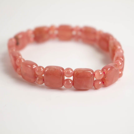 A bracelet made of small, round, pink beads arranged in a row.