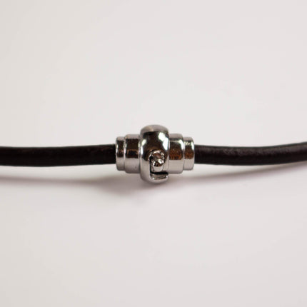 A close-up view of a silver clasp on a black cord or string.