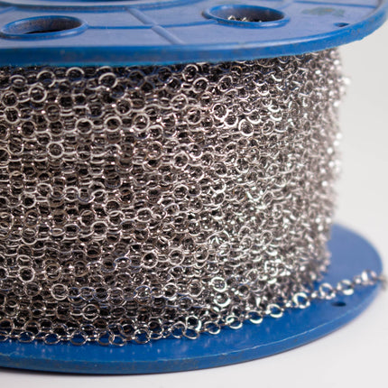 A close-up image of a spool of silver metal chain against a blue background.