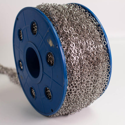 A spool of silver metal chain with a blue plastic spool holder.