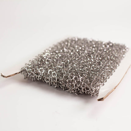 A close-up image of a piece of silver mesh or chain against a white background.
