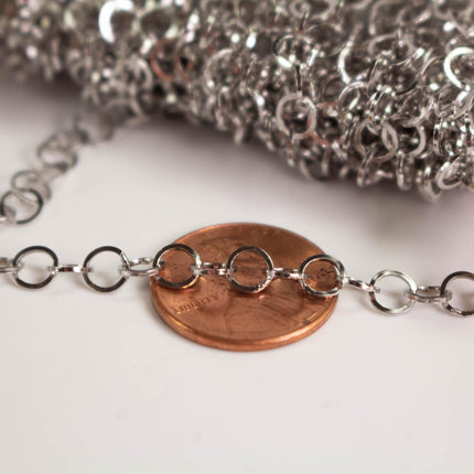 a close-up view of a chain of small silver rings resting on a copper-colored penny.