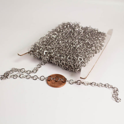 a close-up view of a silver chain with a copper-colored coin placed on a white surface.