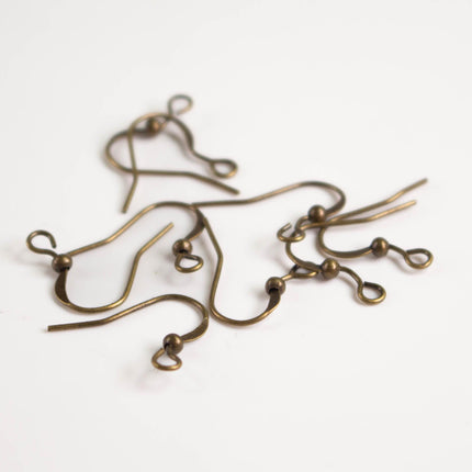 A group of brass ear hooks with a twisted, coiled shape and small circular beads attached to them.