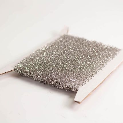 A close-up image of a piece of silver wire or metal mesh with a textured, metallic appearance.