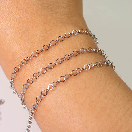 A close-up view of a person's wrist wearing a silver chain bracelet with multiple circular links.
