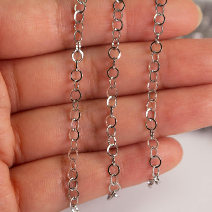 A close-up image of a person's hand holding a chain with multiple silver-colored metal links.