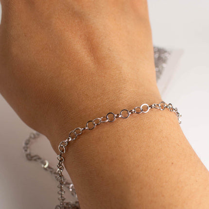 A close-up view of a person's wrist wearing a silver chain bracelet.