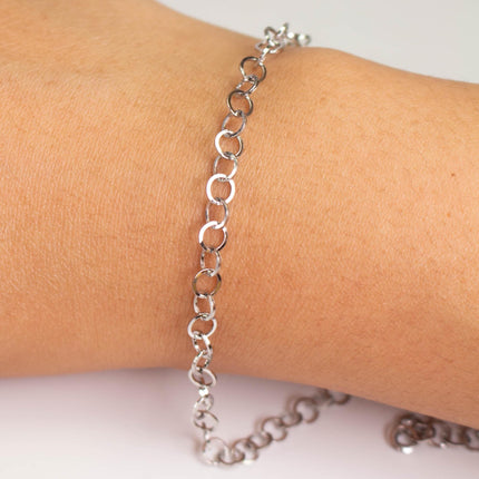 A silver bracelet is worn on a person's wrist.