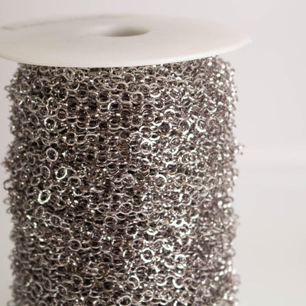 A close-up image of a spool of silver-colored metal chain against a white background.